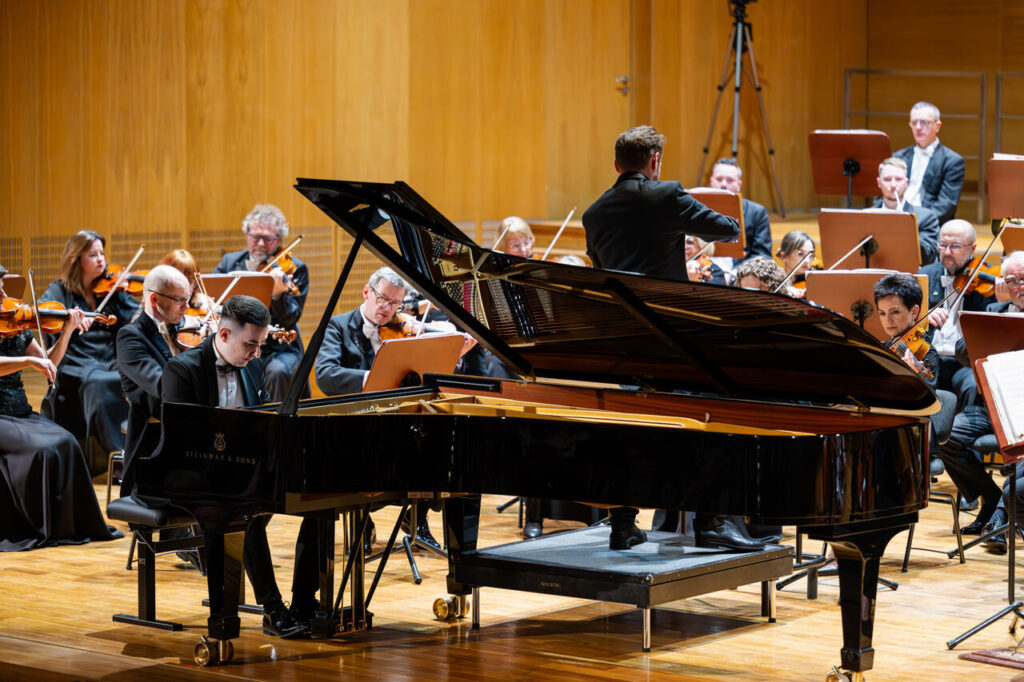 Dominik Gilewski (fortepian) i Orkiestra Symfoniczna Filharmonii Podkarpackiej pod batutą Piotra Kościka, w czasie koncertu symfonicznego